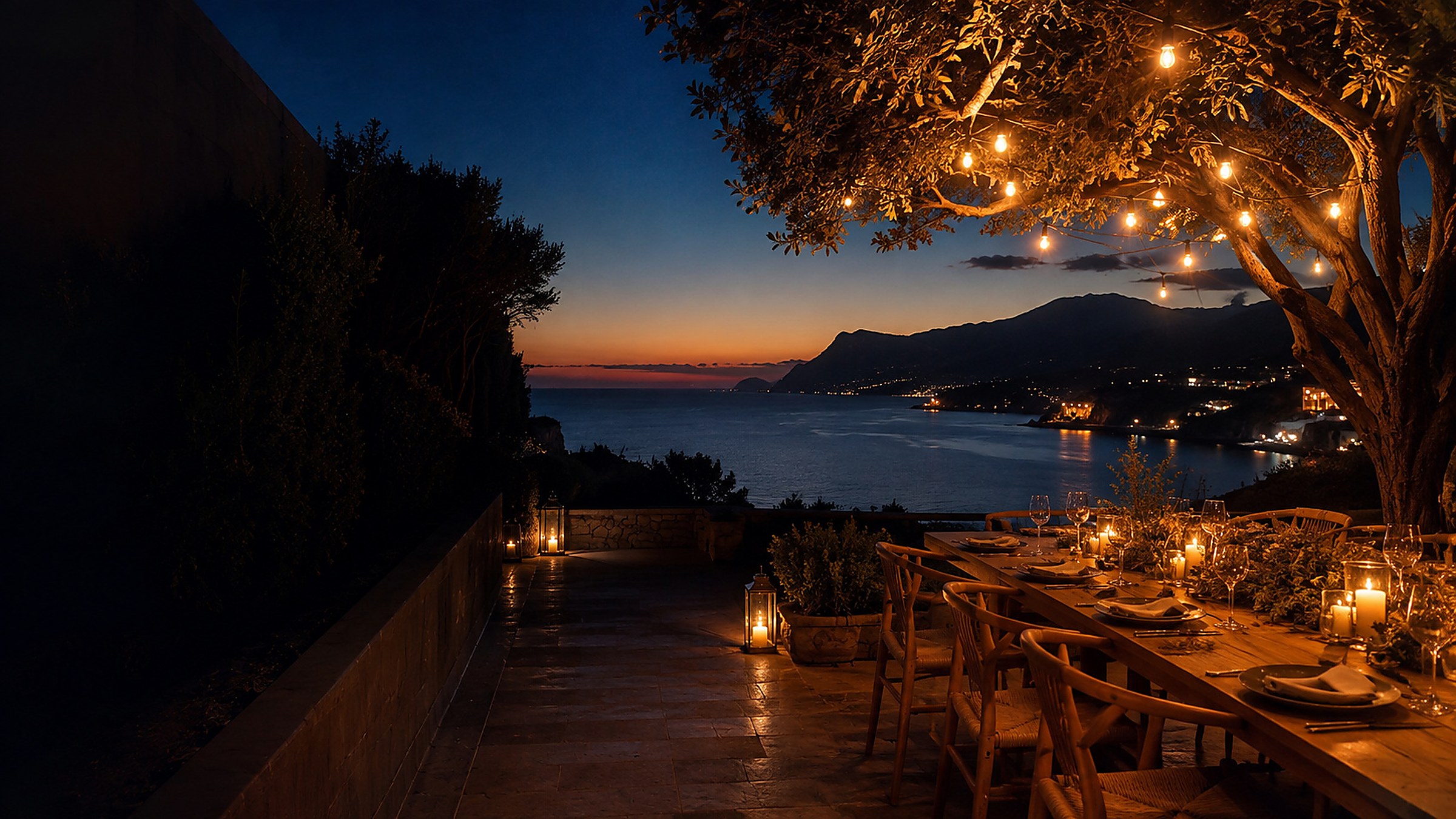 Table dressée sur une terrasse au bord de la mer à la tombée de la nuit